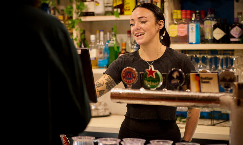 Bar staff serving behind a pub bar with taps